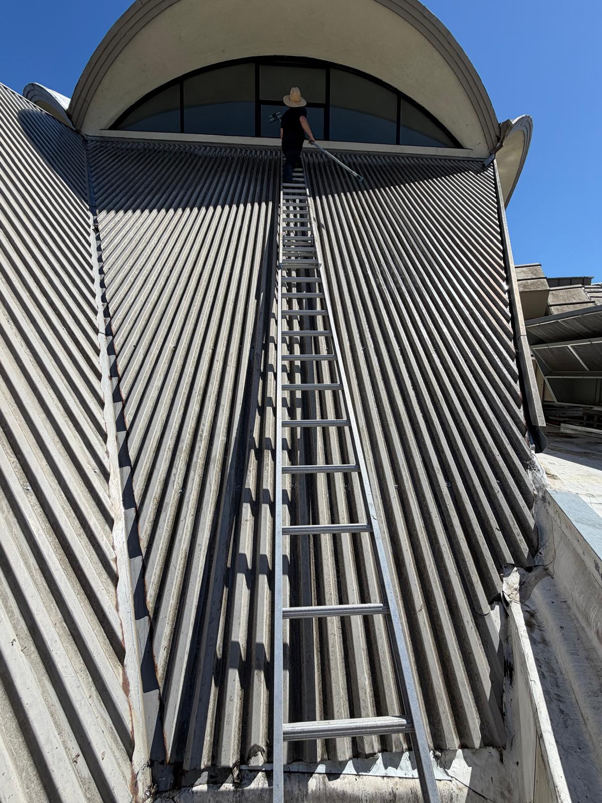Tall extension ladder setup on church metal roof